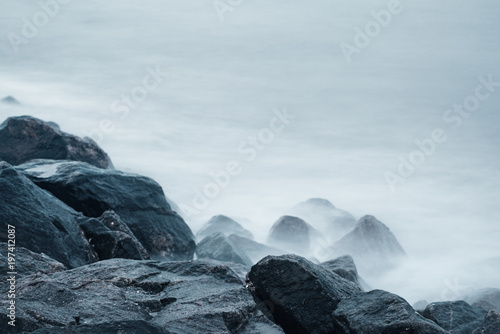 Dreamy natural background with sea shore, rocks and waves. Long exposure. Black and white