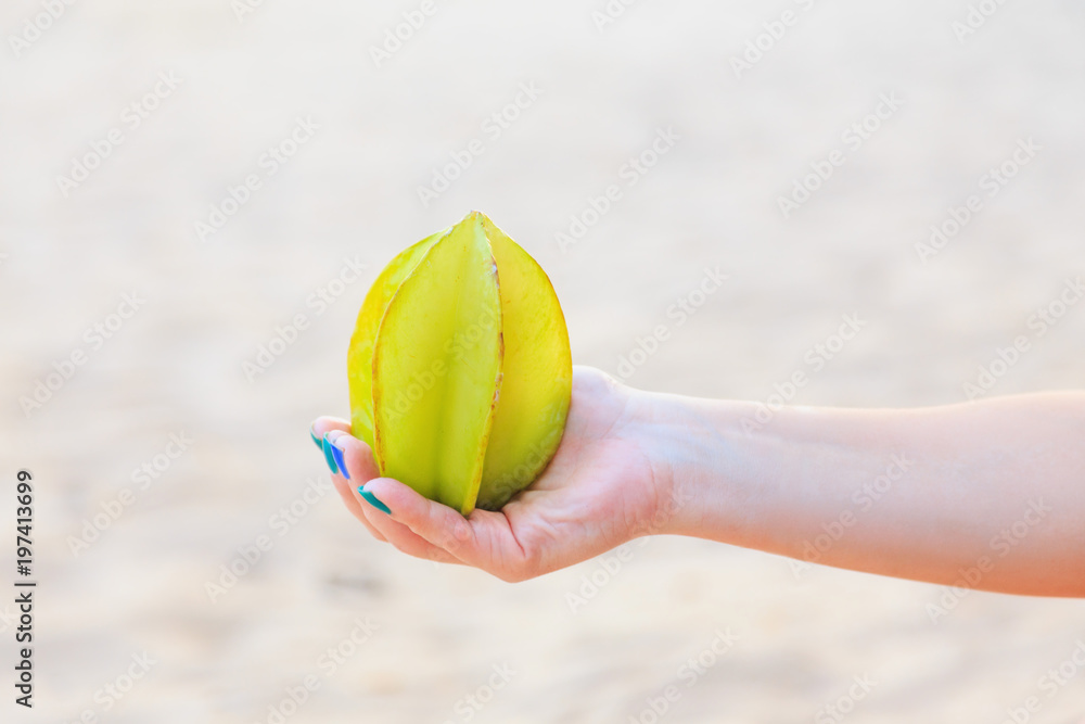 whole exotic carambola fruit on a female hand