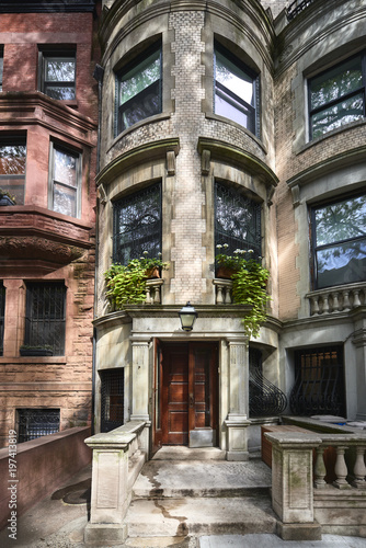 A view of a historic brownstone on a sunny summer day in an iconic neighborhood of Manhattan, New York City.