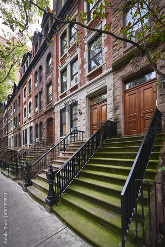 a row of brownstone buildings and stoops in an iconic neighborhood of Manhattan  New York City.
