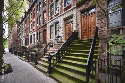 a row of brownstone buildings and stoops in an iconic neighborhood of Manhattan, New York City.