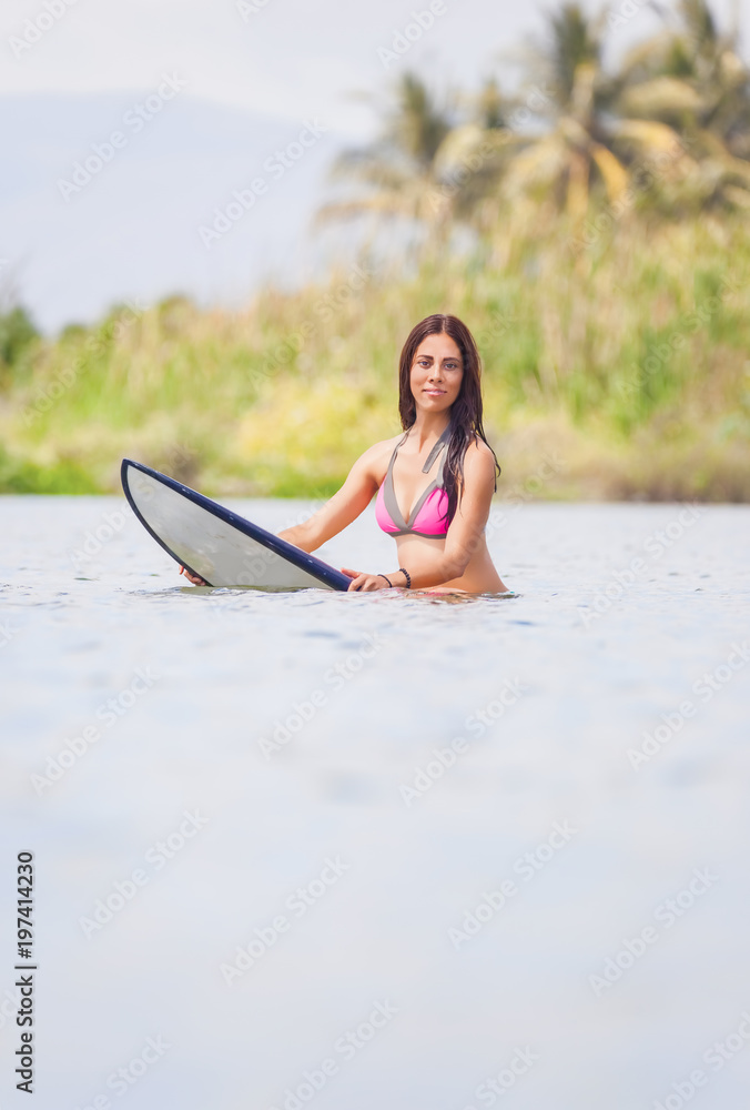 Surfer girl sitzt auf einem Surfbrett