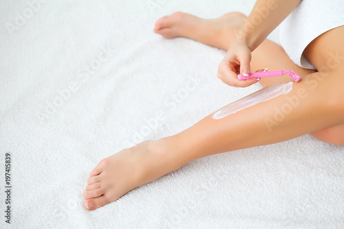 Young woman removing hair on legs with razor. Body care and shaving every day. Smooth skin.