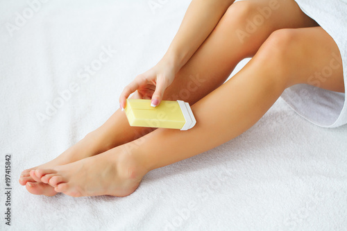 Women receive waxing for hair removal in her bathroom
