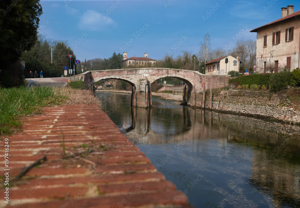 ancient bridge with two arches on the waterway near Milan, Italy