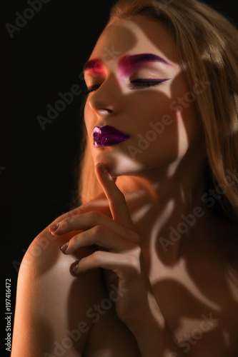 Young woman with dyed eyebrows in darkness