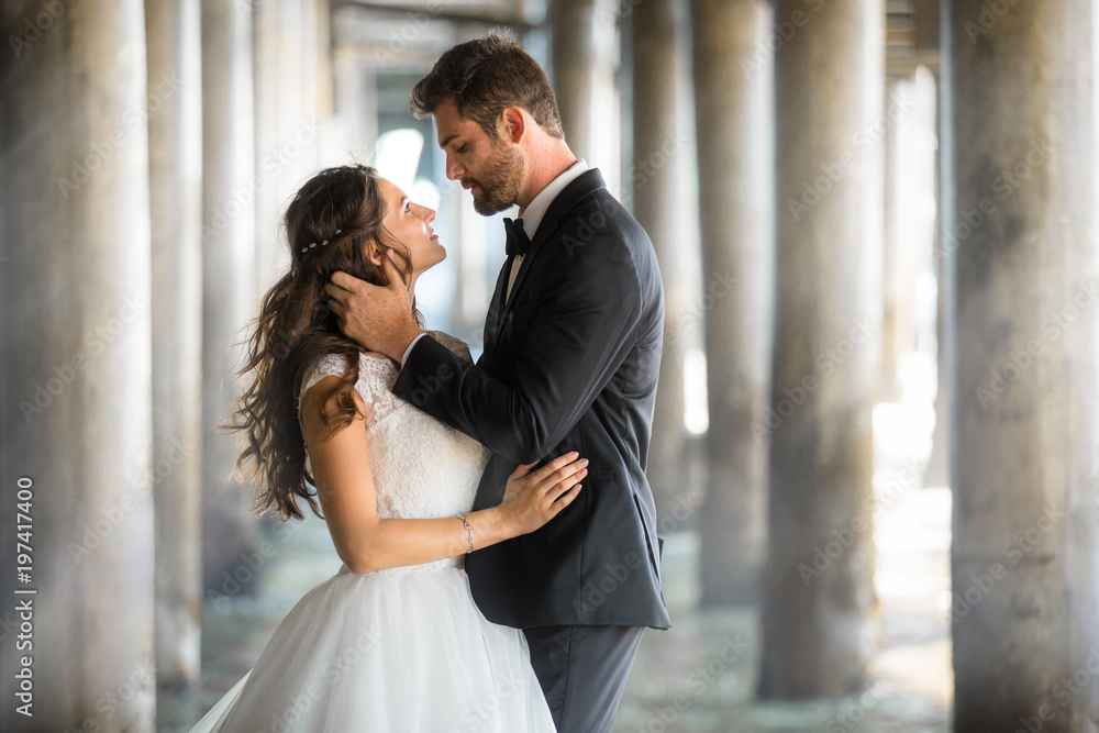 Stunning artistic portrait of bride and groom in love embracing with gorgeous background