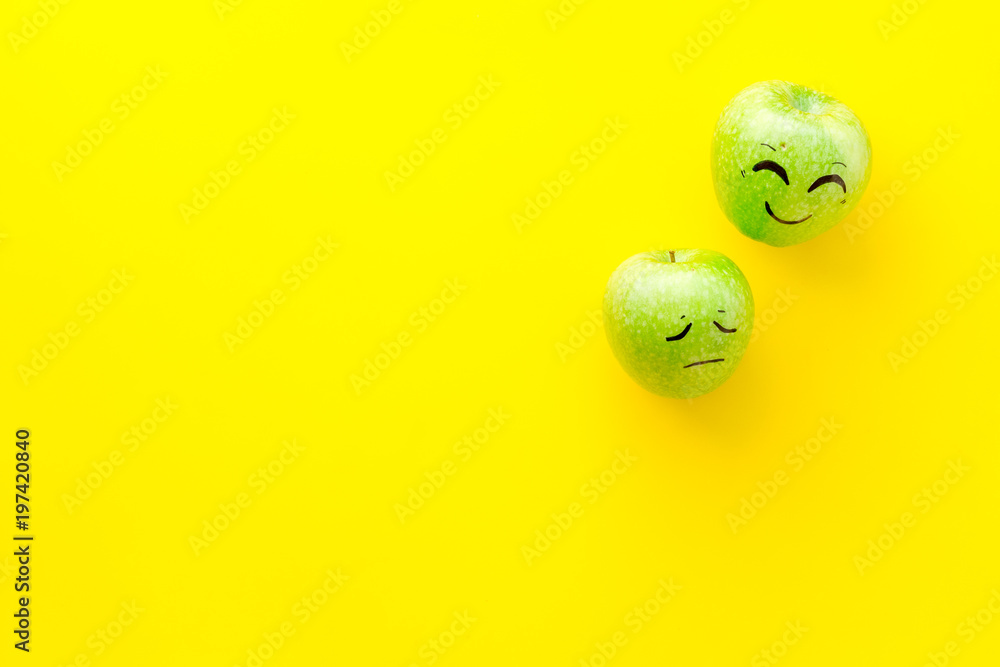 Emotion management concept. Happy and Sad. Face drawn on apple. Yellow background top view copy space Emotion management concept. Happy and Sad. Face drawn on apple. Yellow background top view copy space
