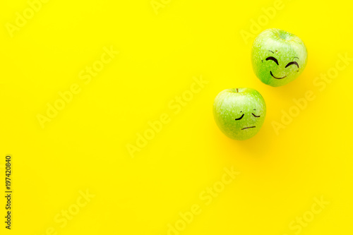 Emotion management concept. Happy and Sad. Face drawn on apple. Yellow background top view copy space