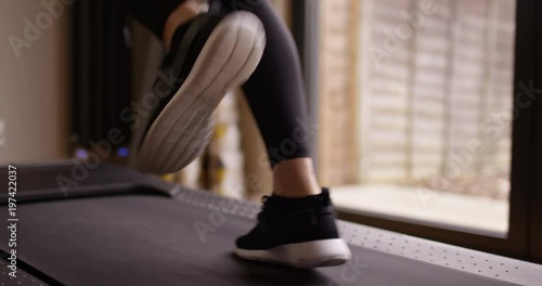 4K Close up on feet of unrecognizable woman working out on running machine. Slow motion.