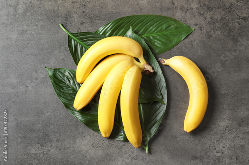 Fresh ripe bananas with leaves on gray background