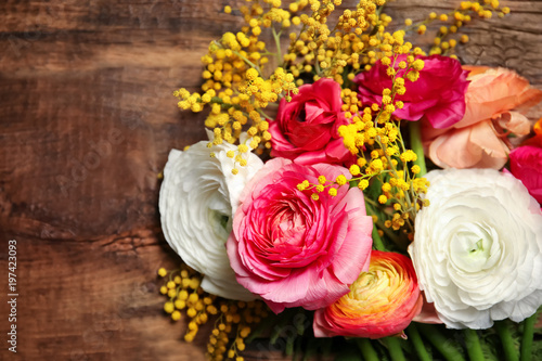 Beautiful ranunculus and mimosa flowers on wooden background