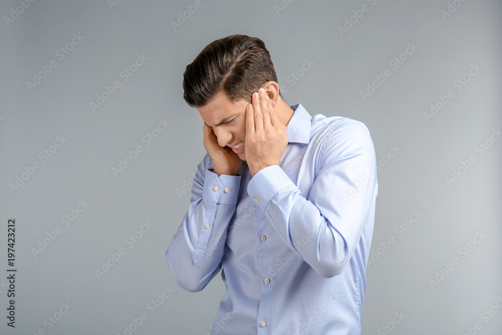 Young man suffering from headache on grey background Young man suffering from headache on grey background