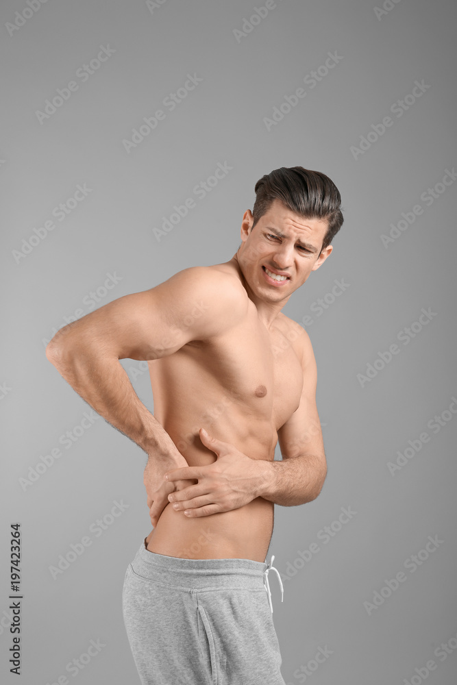 Young man suffering from flank pain on grey background Stock Photo