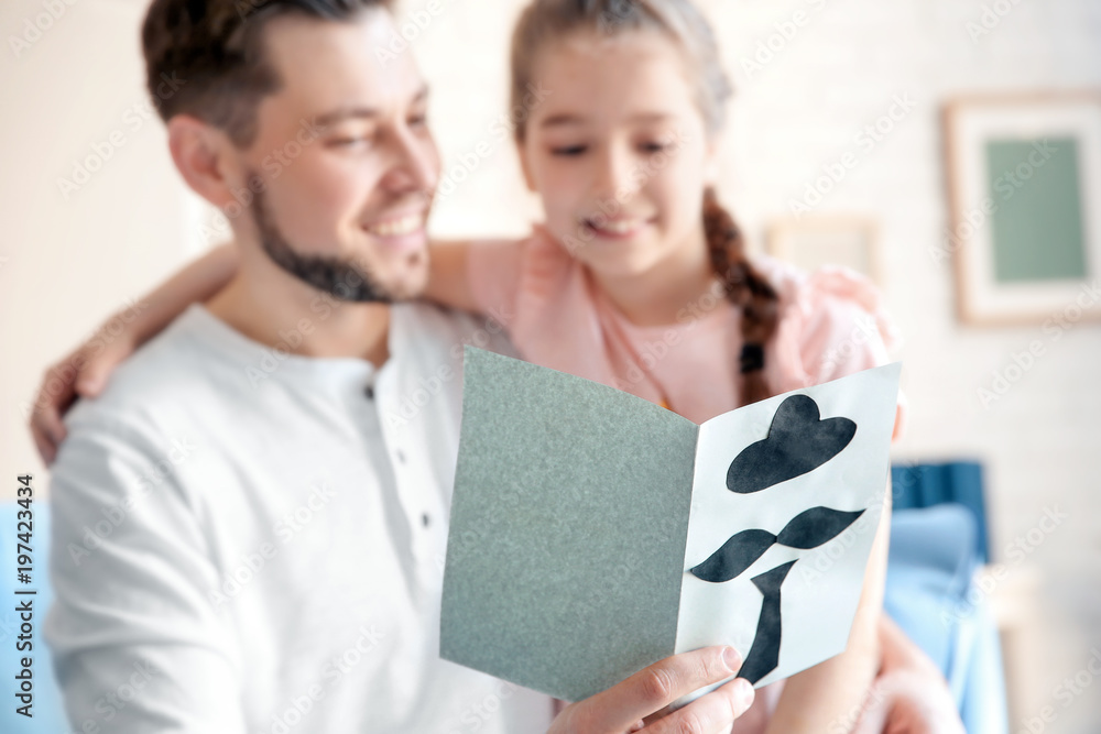 Little girl greeting her dad with Father's Day at home