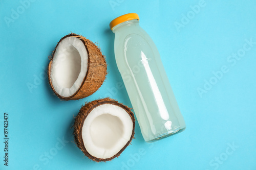 Bottle of coconut water and fresh nuts on color background