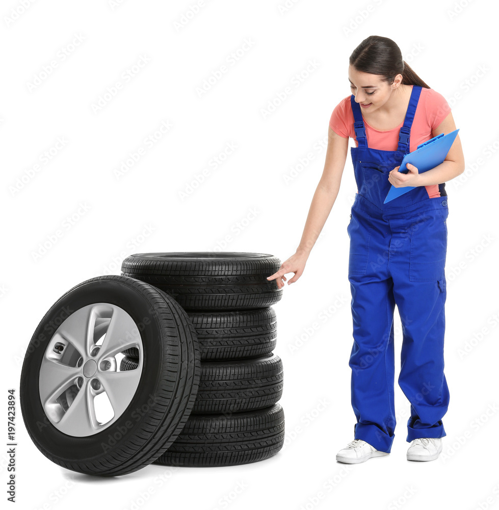 Female mechanic in uniform with car tires and clipboard on white background Female mechanic in uniform with car tires and clipboard on white background