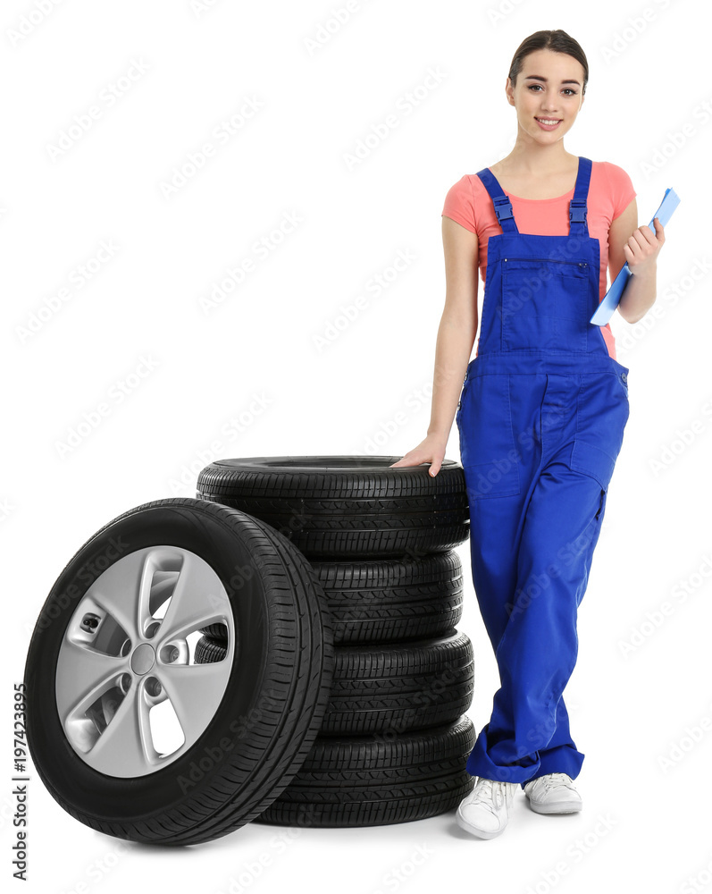 Female mechanic in uniform with car tires and clipboard on white background Female mechanic in uniform with car tires and clipboard on white background