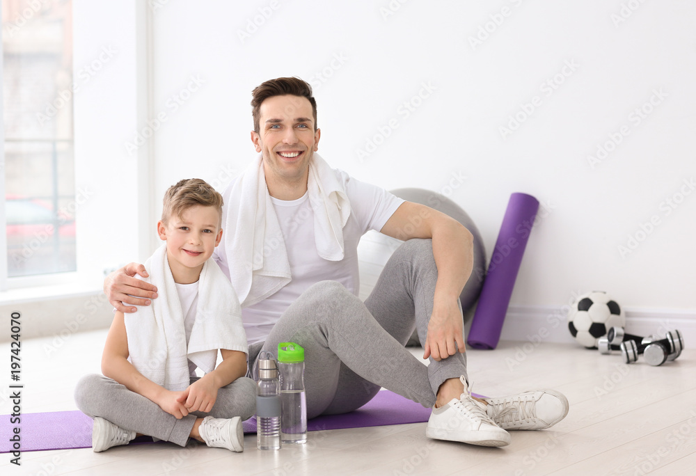 Dad and his son with bottles of water in gym Dad and his son with bottles of water in gym