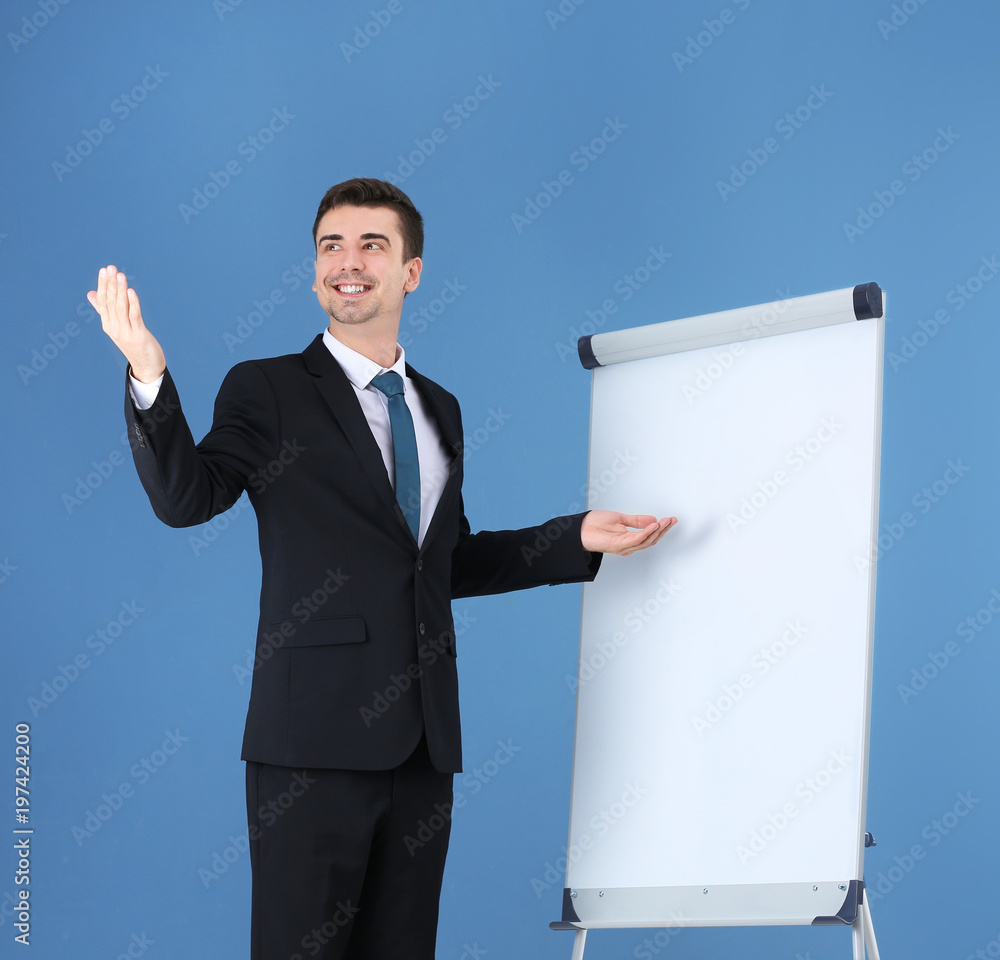 Business trainer giving presentation on flip chart board against color background Business trainer giving presentation on flip chart board against color background