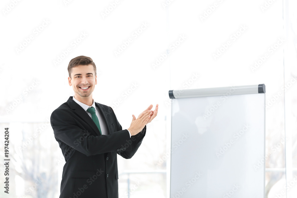 Business trainer applauding near flip chart board indoors Business trainer applauding near flip chart board indoors