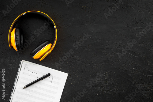 Fotografie Work space of composer or dj with headphones and notes black background top view
