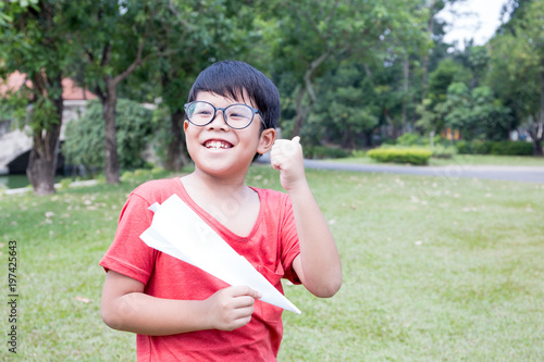 Asian boy in red t-shirt dress play with a paper rocker and thumbs up with  garden  scene