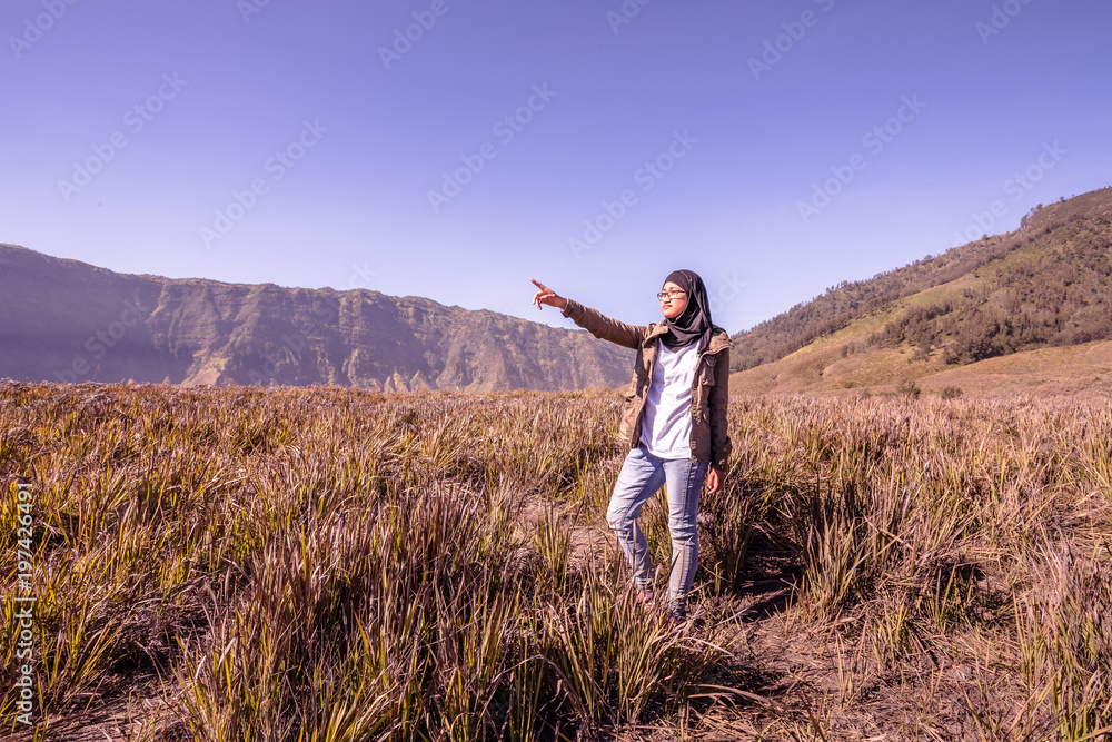 A teenager pose with Bromo mountain as background at East Java Indonesia A teenager pose with Bromo mountain as background at East Java Indonesia