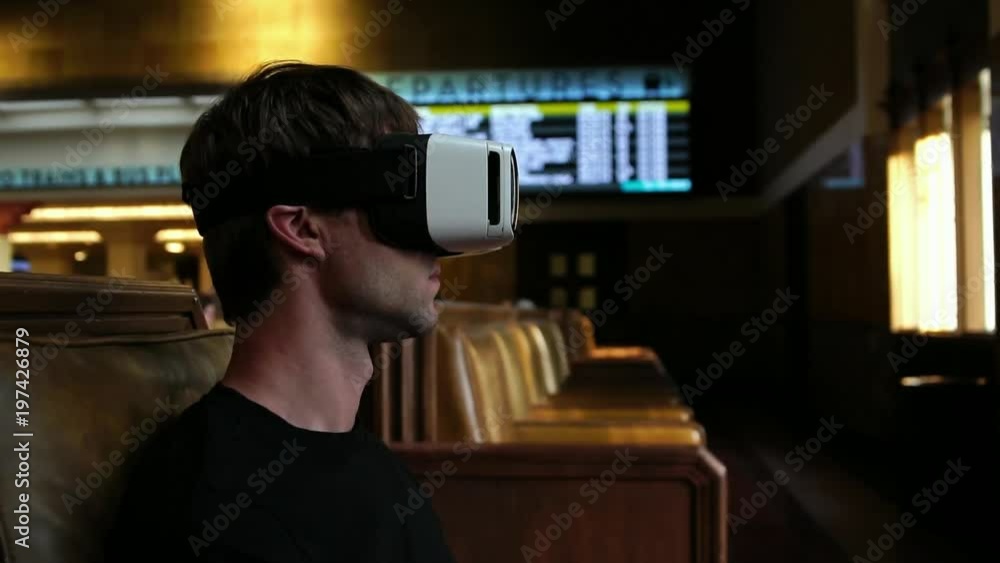 Young man wearing virtual reality headset watching 360 video in train union station Young man wearing virtual reality headset watching 360 video in train union station