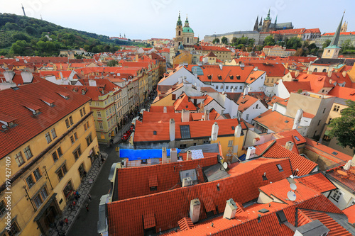 Aerial view of Prague Old Town, capital of Czech Republic & a UNESCO heritage city, with the castle on a hilltop, St. Nicholas Church in Lesser Town & red rooftops of historical houses by a street 