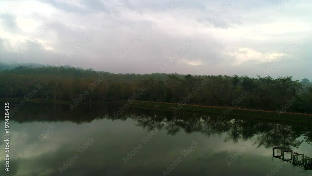 4k Aerial Top view Natural Forest Mountain with reservoir and cloudy and blue sky and fog, Have reflected in the water, Located in Thailand. (Movement Track-out) 4k Aerial Top view Natural Forest Mountain with reservoir and cloudy and blue sky and fog, Have reflected in the water, Located in Thailand. (Movement Track-out)