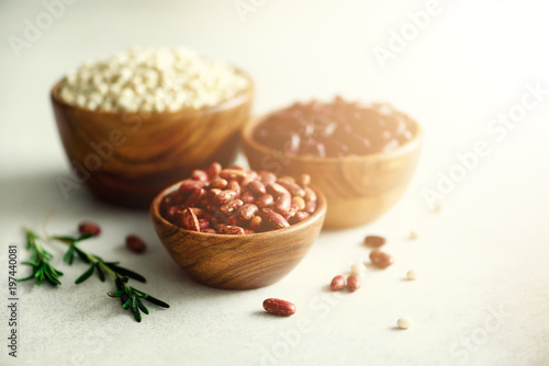 Various of kidney beans. Red, white and black kidney beans in wooden bowls with rosemary on grey concrete background. Copy space, banner