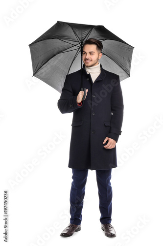 Young man in warm coat with dark umbrella on white background