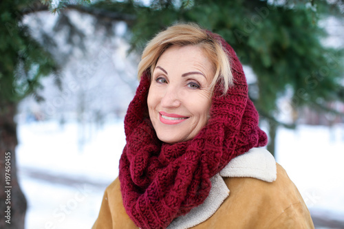 Portrait of happy mature woman in snowy park on winter vacation