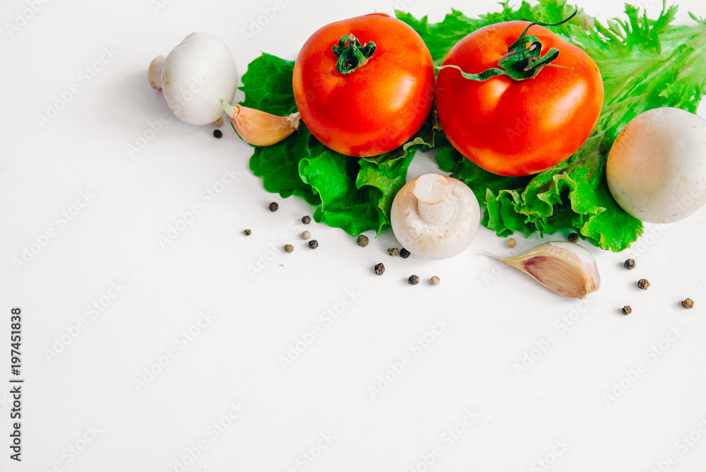Fresh assorted vegetables tomatoes, mushrooms, garlic, lettuce leaves. Isolated on white background. Selective focus. With place for you own text message Fresh assorted vegetables tomatoes, mushrooms, garlic, lettuce leaves. Isolated on white background. Selective focus. With place for you own text message