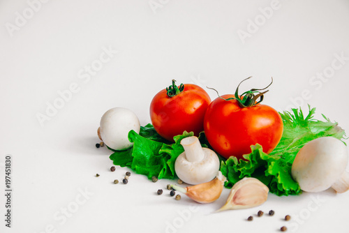 Vegetarian fresh assorted vegetables tomatoes, mushrooms, garlic, lettuce leaves. Isolated on white background. Selective focus. With place for you own message.