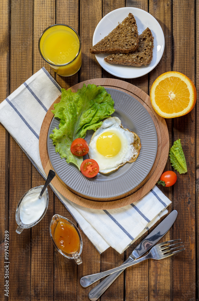 English Breakfast: fried egg, juice, cherry tomatoes, lettuce, grain bread, sauce, top view. English Breakfast: fried egg, juice, cherry tomatoes, lettuce, grain bread, sauce, top view.