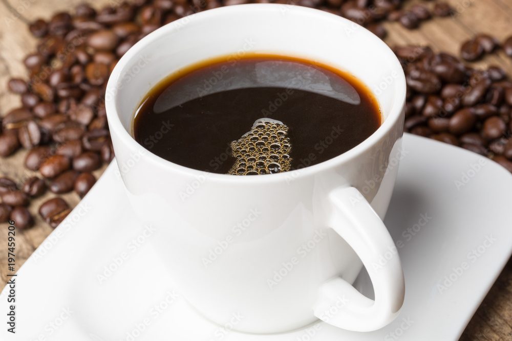 Eine Tasse mit frischem schwarzem Kaffee und Kaffeebohnen Eine Tasse mit frischem schwarzem Kaffee und Kaffeebohnen
