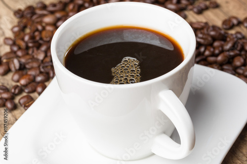 Eine Tasse mit frischem schwarzem Kaffee und Kaffeebohnen