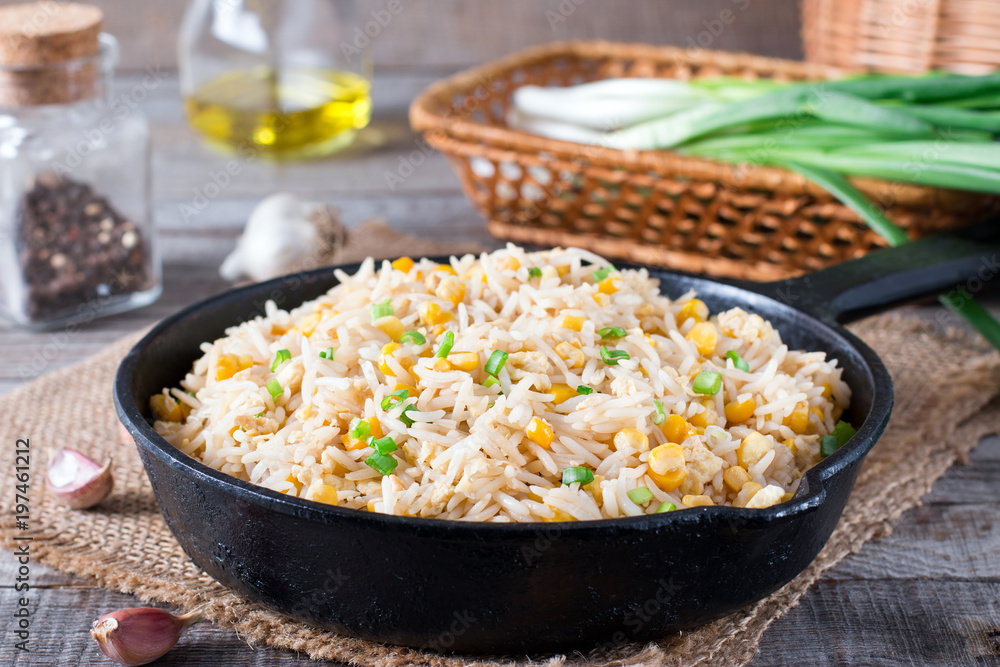 Asian fried rice with eggs and corn in a frying pan on wooden background Asian fried rice with eggs and corn in a frying pan on wooden background