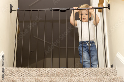 Funny toddler approaching safety gate of stairs