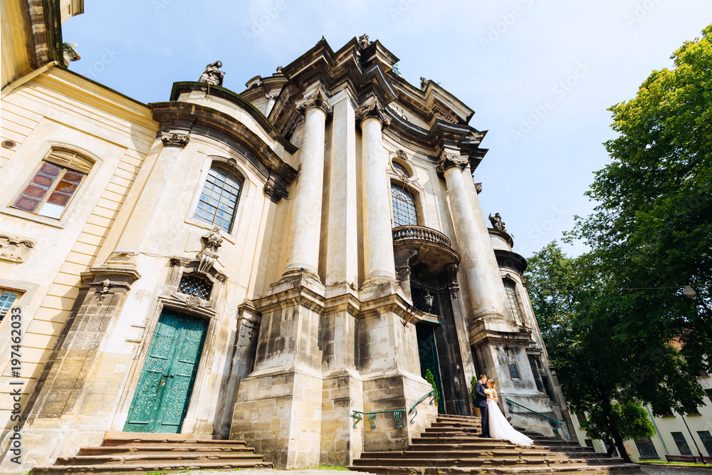 Obraz premium beautiful building with incredible architecture and newlyweds standing on the stairs