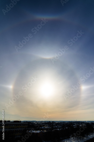 Varoious sun halos arc appearing in the winter sky in the city with birds flying. Rare natural phenomenon. Upper tangent arc. © Arseniy
