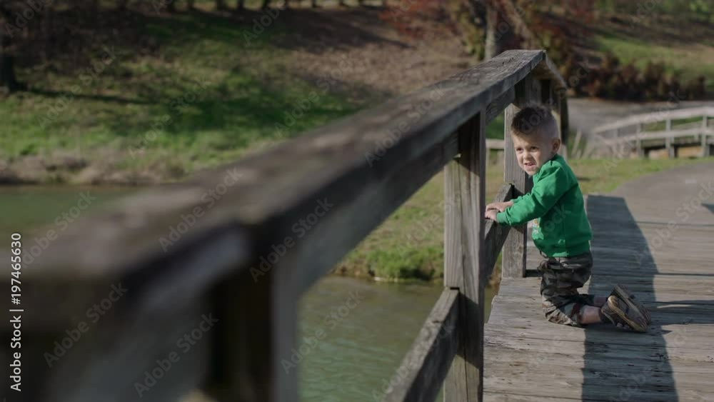 Little boy on the beautiful wooden bridge in park 4k Little boy on the beautiful wooden bridge in park 4k