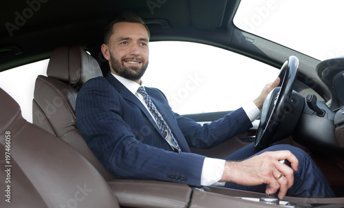 View from the side confident businessman sits at the wheel of a car © ASDF