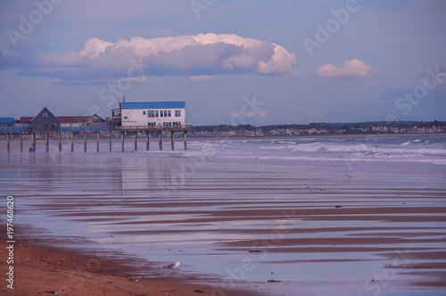 Interesting wooden houses on the pier above the water, the Atlantic coastline at low tide. Maine, United States, Portland. Beautiful sea view.   © Ann Stryzhekin