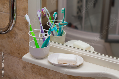 White bath accessories: bar of soap in soap-dish, liquid soap, toothbrushes