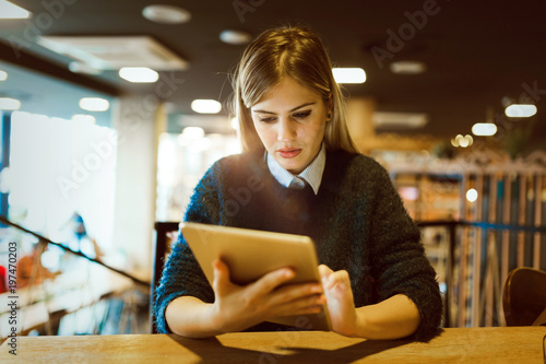 Happy young woman drinking coffee and using tablet
