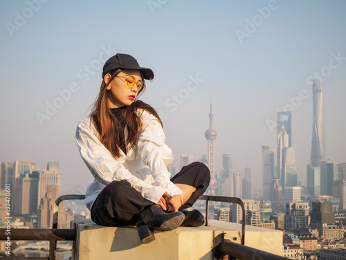 Photography Beautiful young brunette woman sit on top of mansion roof with blur Shanghai Bund landmark buildings background
