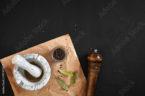 White mortar and pestle with dried peppers in flat lay on black background photo